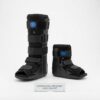 Product photograph showing a side-by-side comparison of a long and a short orthopedic pneumatic walker boot, both black with blue air valves and adjustable straps, displayed on a white background with a descriptive acrylic plaque